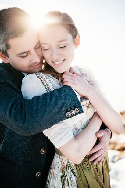 Hochzeitspaar im Dirndl eng umarmt bei Sonnenuntergang