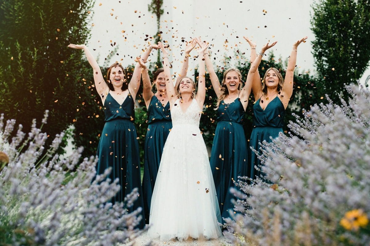 Braut mit ihren Brautjungfern wirft Blüten in die Luft und alle haben eine Freude